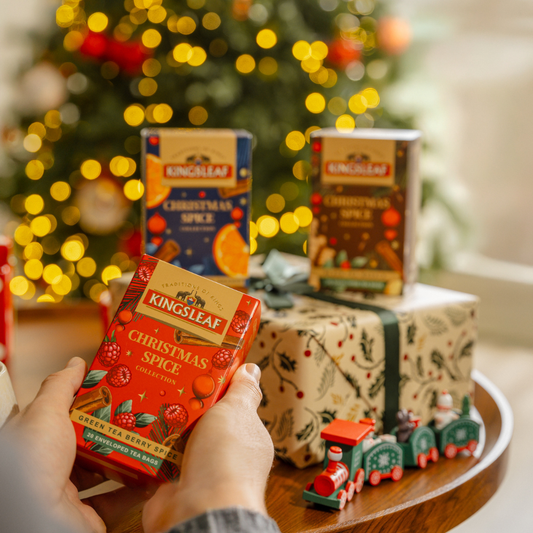 Zestaw herbat Kingsleaf Christmas Spice trzymany przy choince i świątecznych prezentach