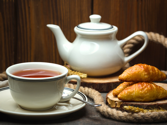 Filiżanka czarnej herbaty podana z croissantami.