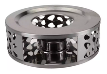 Metalowy podgrzewacz do dzbanka z miejscem na tealight prezentowany z boku w dekoracyjnym wzorze.