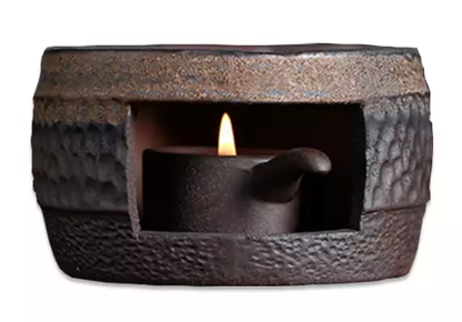 Podgrzewacz ceramiczny okrągły 9 cm w kolorze ciemnym, z palącą się świeczką tealight wewnątrz.