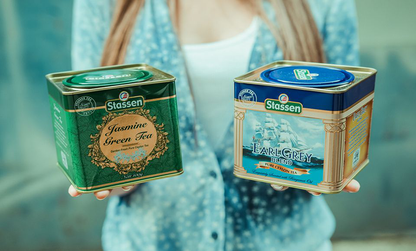 Kobieta trzymająca puszki herbat Stassen Jasmine Green Tea i Earl Grey, zielona herbata z jaśminem.