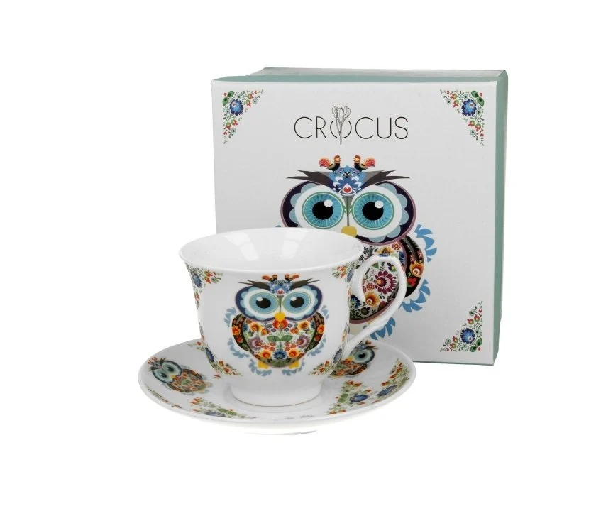 Filiżanka porcelanowa ze spodkiem Sowa Etno ustawiona przed ozdobnym pudełkiem.
