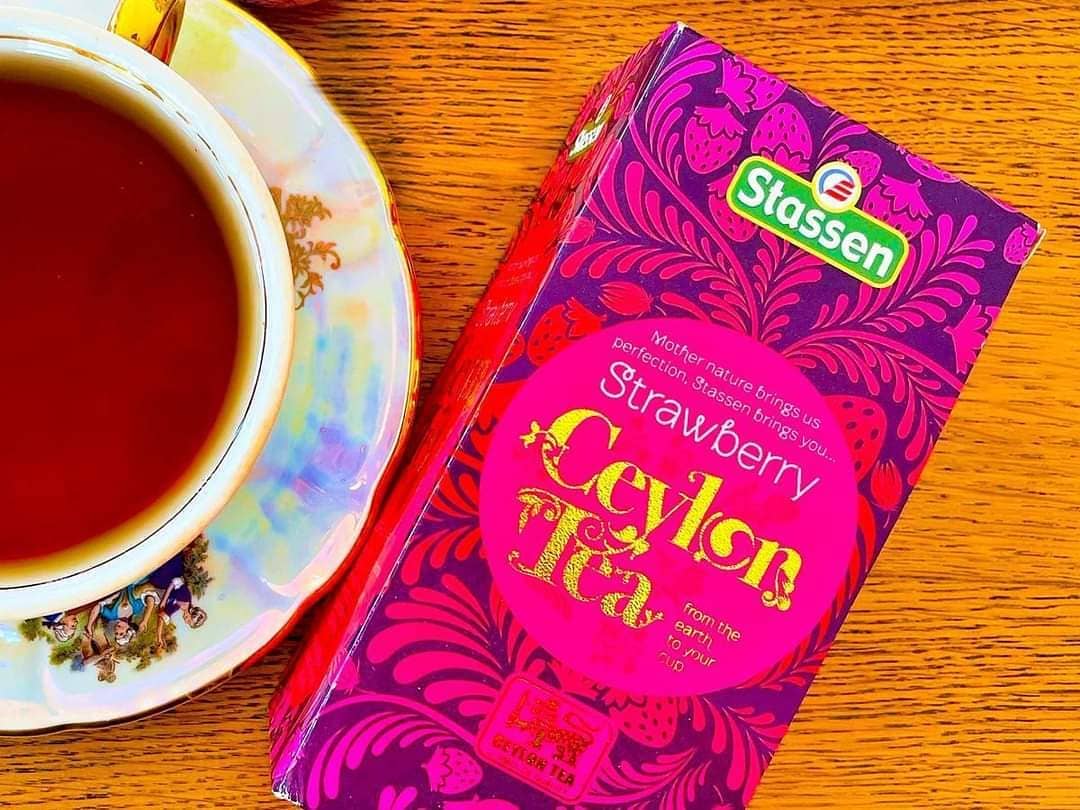 Pudełko herbaty Stassen Strawberry Tea obok filiżanki naparu – 25 saszetek.
