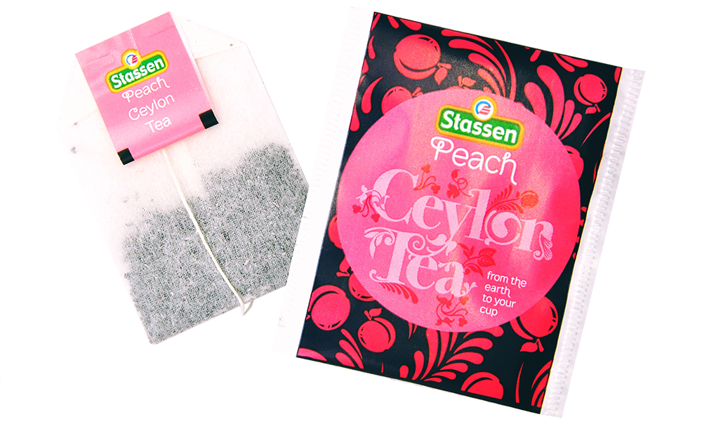 Torebka herbaty i saszetka Stassen Peach Tea ułożone pod kątem – owocowa herbata cejlońska.