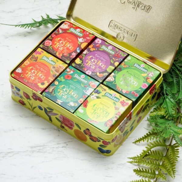 Kolorowe pudełka herbat Stassen obok filiżanki naparu i kwiatów.