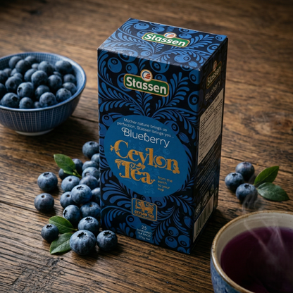 Herbata Stassen Blueberry Ceylon Tea 25 torebek z borówkami i filiżanką fioletowego naparu na drewnianym blacie.