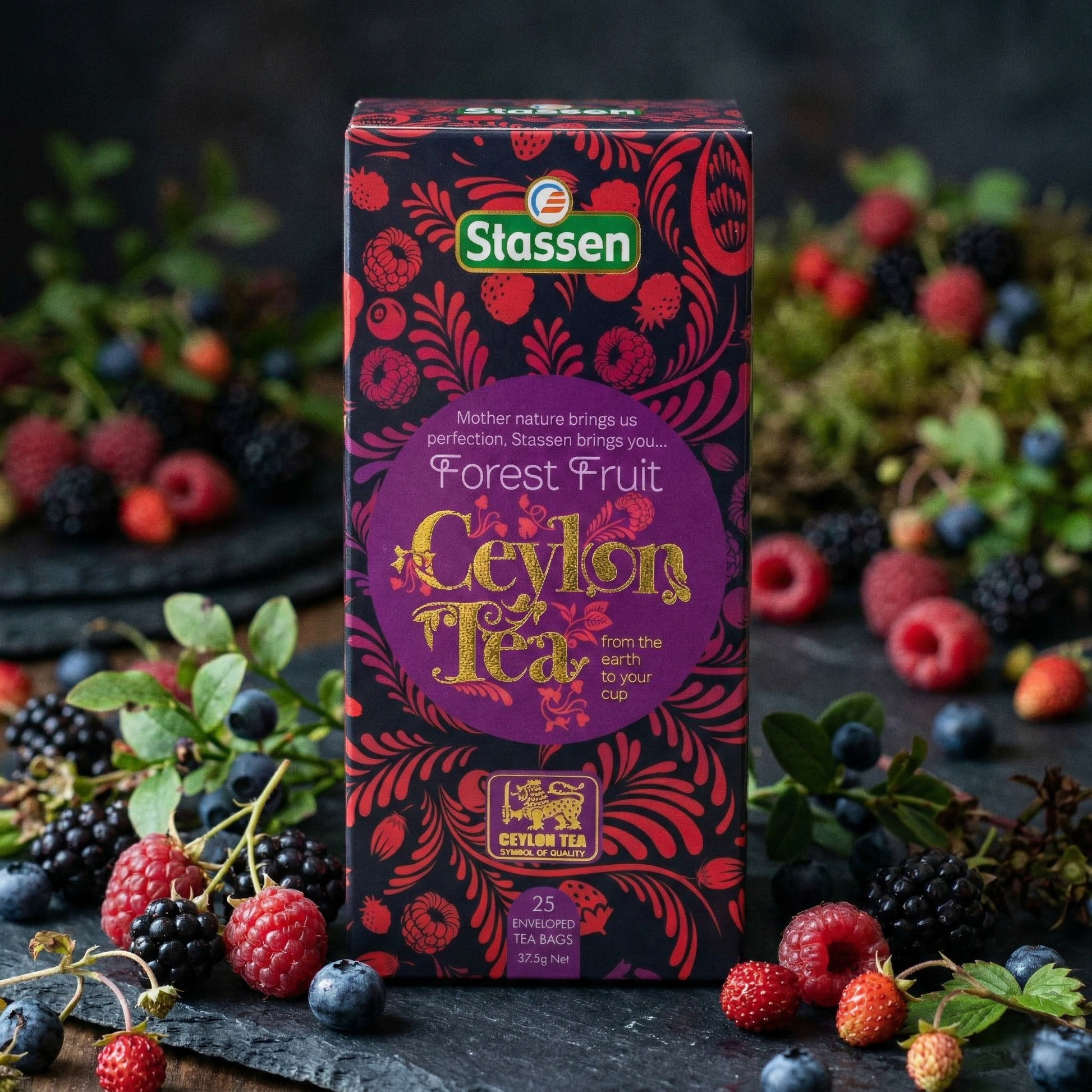 Herbata Stassen Forest Fruit Ceylon Tea 25 torebek w opakowaniu z motywem owoców leśnych, wśród malin, jeżyn i borówek.