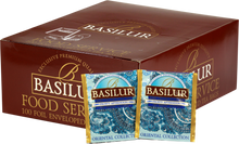 Opakowanie herbaty Basilur Frosty Afternoon z widocznymi saszetkami czarnej herbaty cejlońskiej w niebiesko-złotych kopertach z orientalnym wzorem.