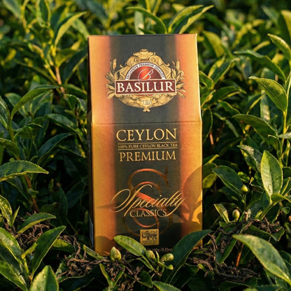 Opakowanie herbaty Basilur Ceylon Premium stojące wśród zielonych krzewów herbaty na plantacji, naturalne światło.