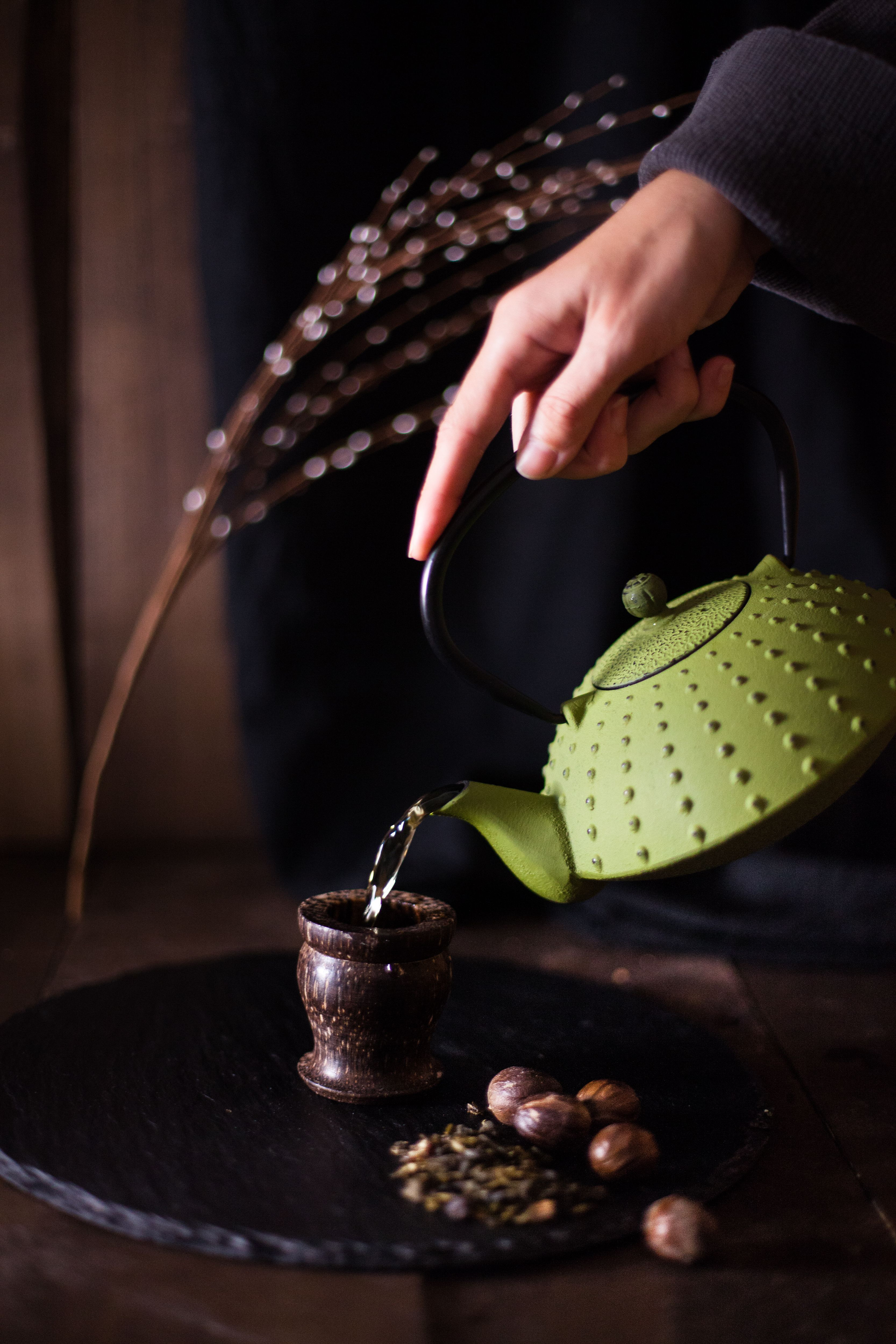 Dzbanek żeliwny Basilur w kolorze zielonym podczas nalewania herbaty do kubka.