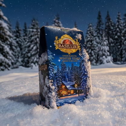 Opakowanie herbaty Basilur Winter Stars stojące w śniegu na tle zimowego lasu, klimatyczna zimowa herbata liściasta na chłodne dni