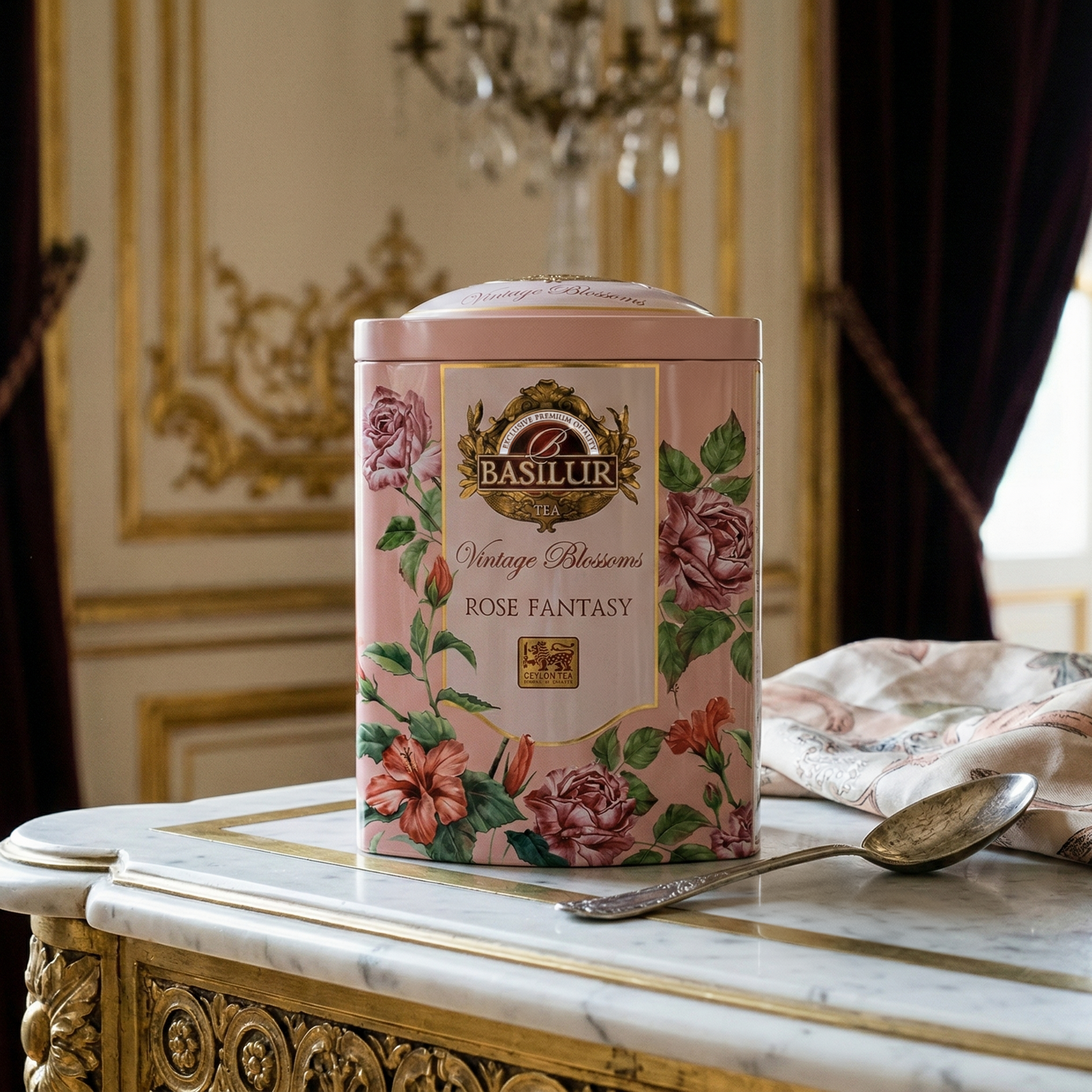 Różowa puszka herbaty Basilur Rose Fantasy z motywem róż na marmurowym stoliku w eleganckim wnętrzu.
