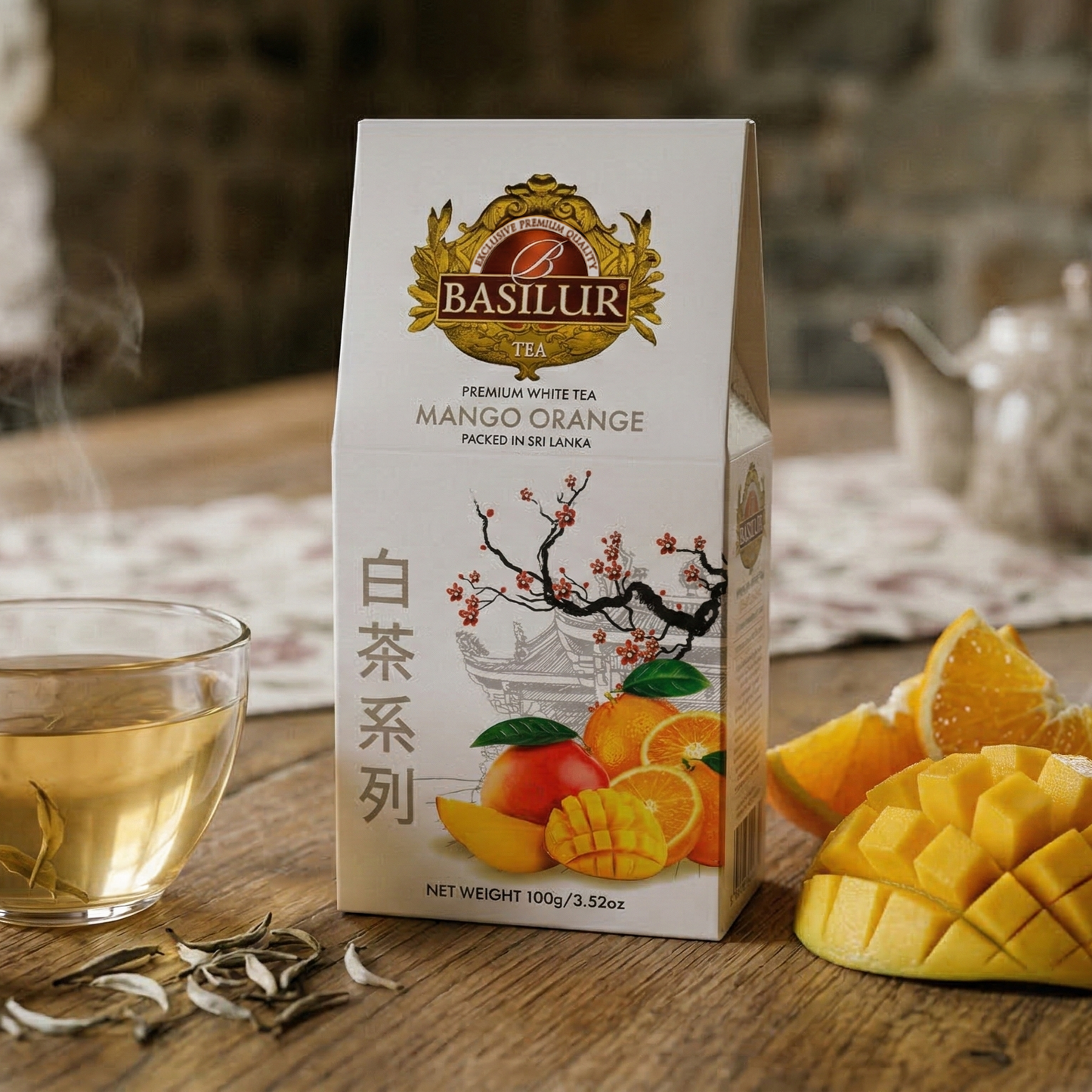 Herbata Basilur Mango Orange w eleganckim opakowaniu obok filiżanki naparu oraz świeżego mango i pomarańczy