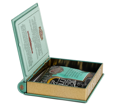 Otwarta puszka Basilur Warmth of Winter vol. I w kształcie książki z opakowaniem herbaty w środku.