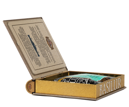 Otwarta puszka Basilur w formie książki z widoczną torebką herbaty w środku