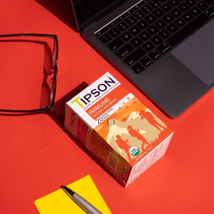 Herbata Tipson Immune Natural Wellbeing ustawiona na biurku obok laptopa i notatnika.