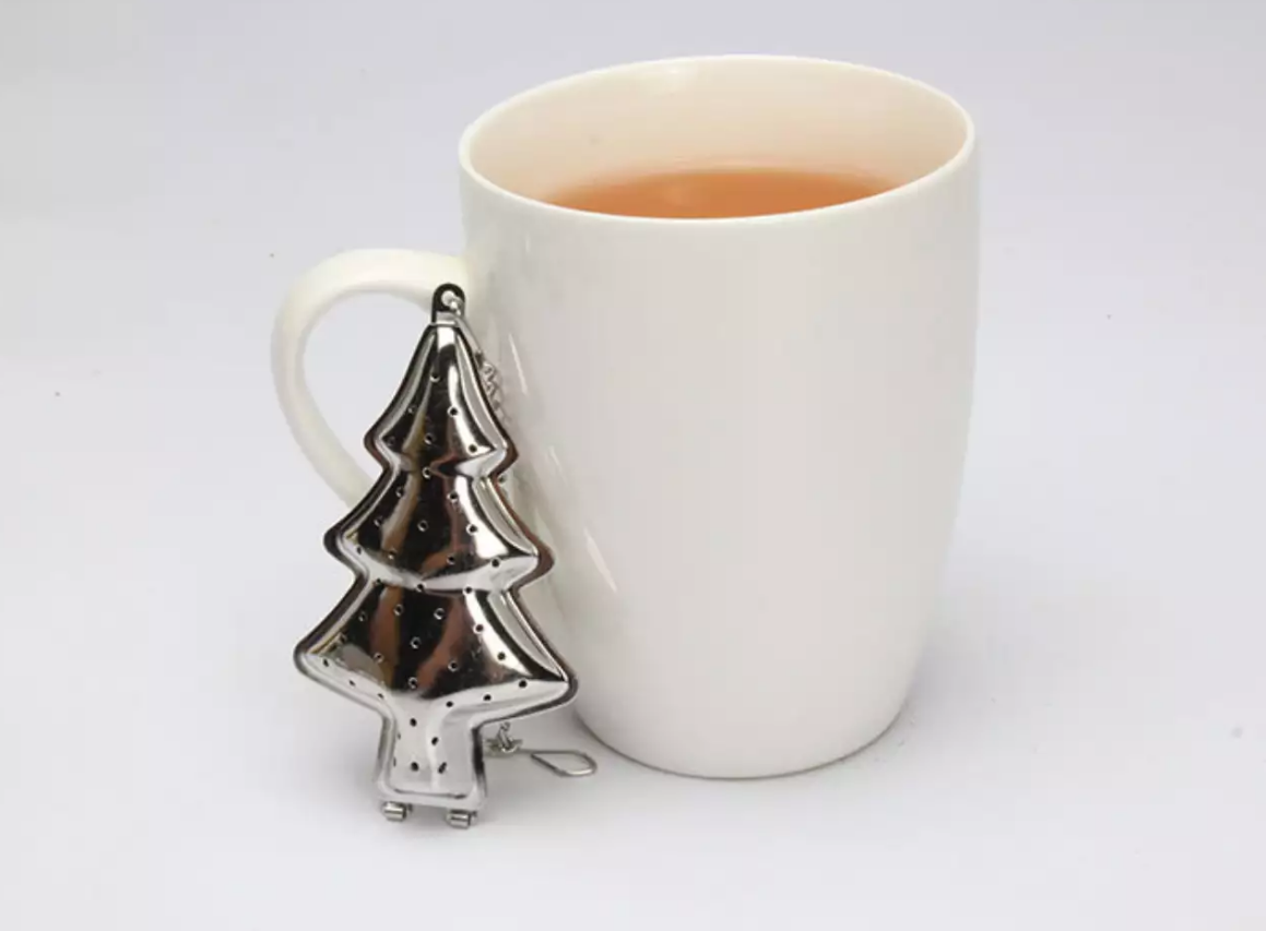 Zaparzacz do herbaty w kształcie choinki ze stali nierdzewnej obok kubka