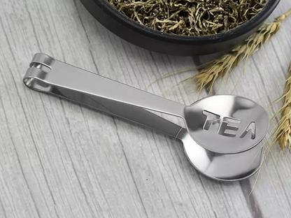 Stalowe szczypce do wyciskania herbaty z napisem TEA – widok z boku.