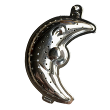 Metalowy zaparzacz do herbaty i ziół w kształcie półksiężyca z perforacją.