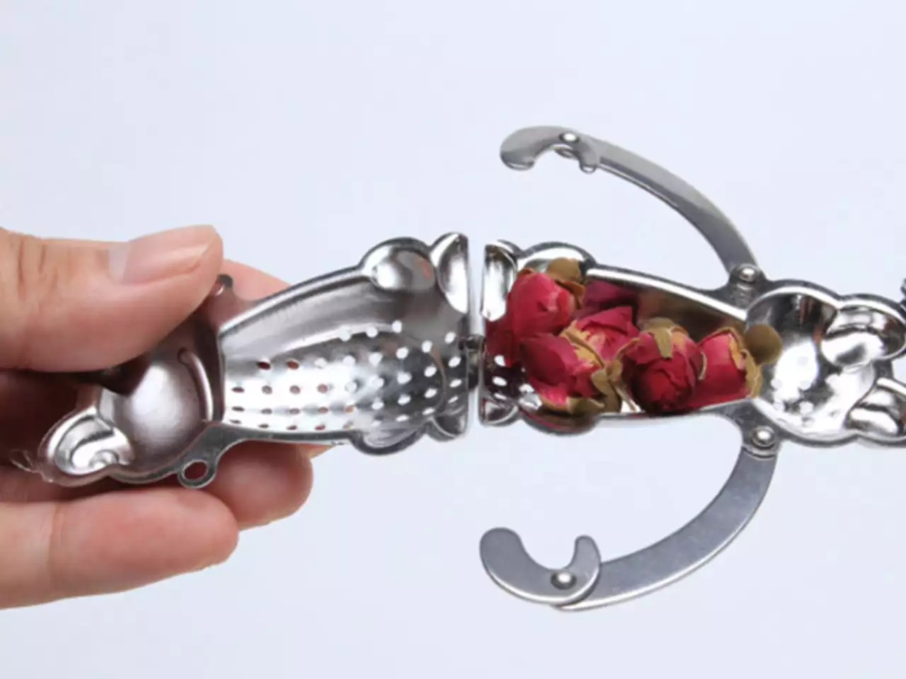 Metalowa żabka-zaparzacz wypełniona suszonymi pąkami róż