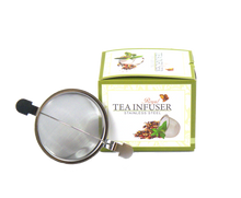 Zaparzacz do herbaty Carmani o średnicy 8,5 cm z metalową siatką i uchwytami, na tle pudełka.