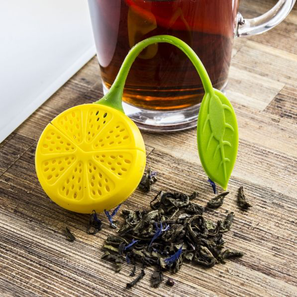 Silikonowy zaparzacz cytryna leżący przy szklance herbaty