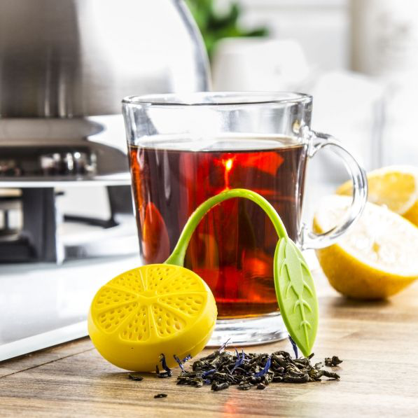 Silikonowy zaparzacz cytryna leżący przy szklance herbaty