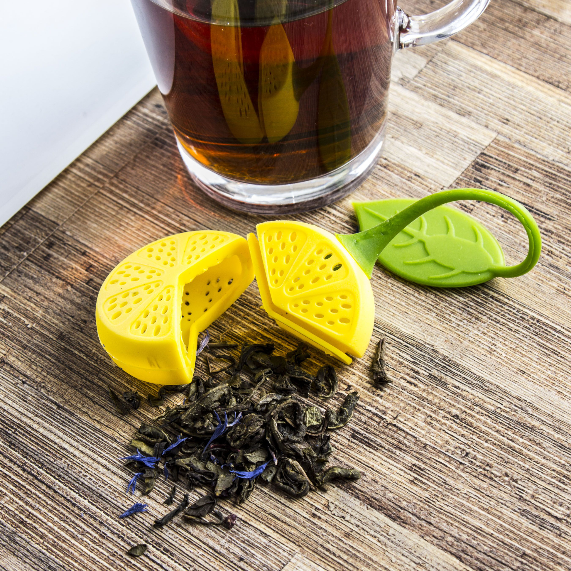 Otwarty zaparzacz do herbaty w kształcie cytryny z liśćmi herbaty