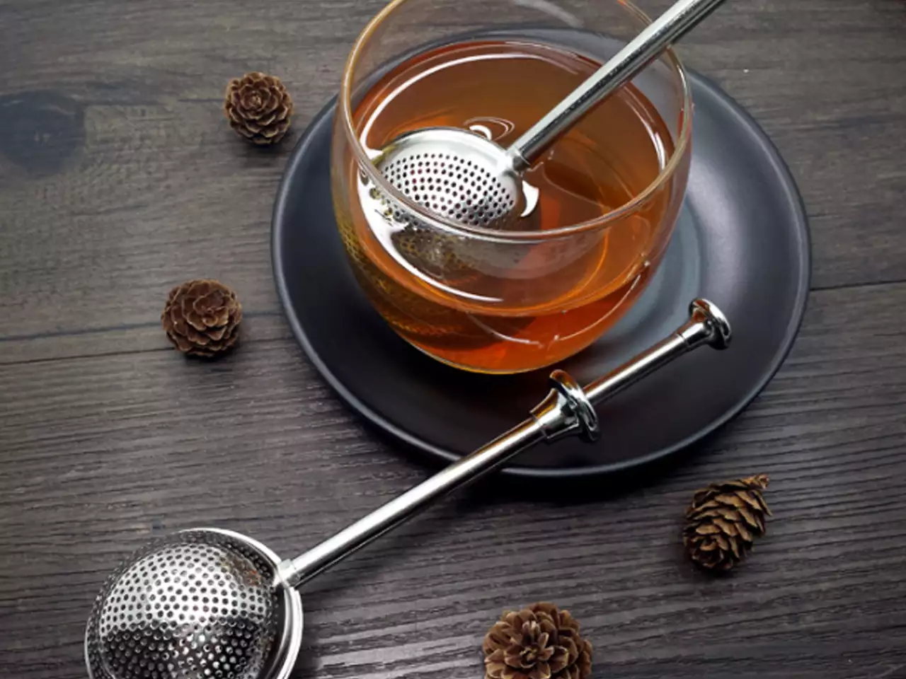 Duża kulka zaparzacz do herbaty i ziół w szklance z naparem.