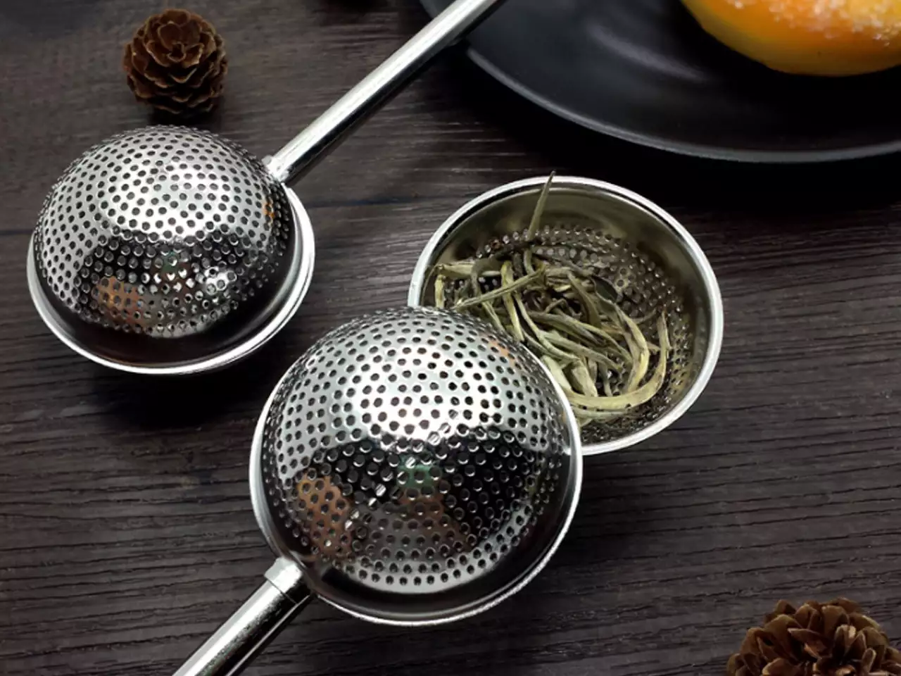 Zaparzacz kulka otwarty z widocznymi liśćmi herbaty.