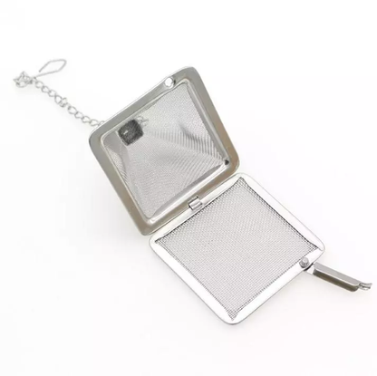 Zaparzacz do herbaty w formie piramidki otwarty, z drobną metalową siatką i łańcuszkiem.