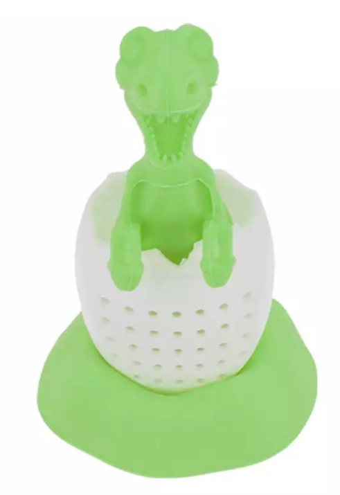 Zbliżenie na zaparzacz do herbaty w kształcie zielonego dinozaura w skorupce jajka.