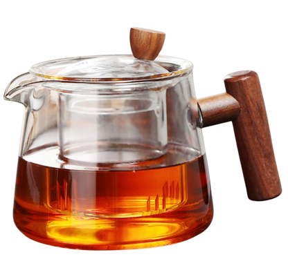 Szklany czajnik z zaparzaczem i drewnianym uchwytem wypełniony herbatą.