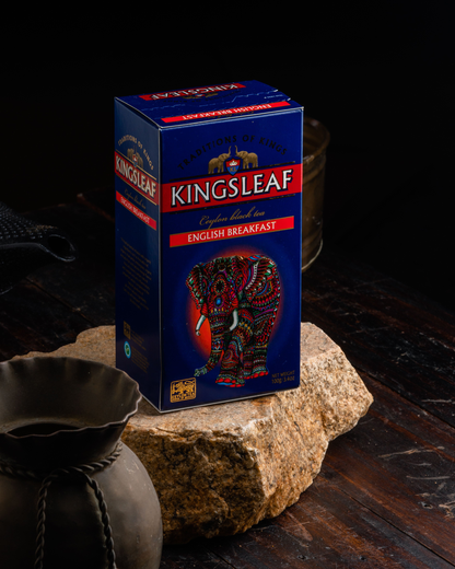 Opakowanie herbaty Kingsleaf English Breakfast ustawione na kamieniu w rustykalnej scenerii.