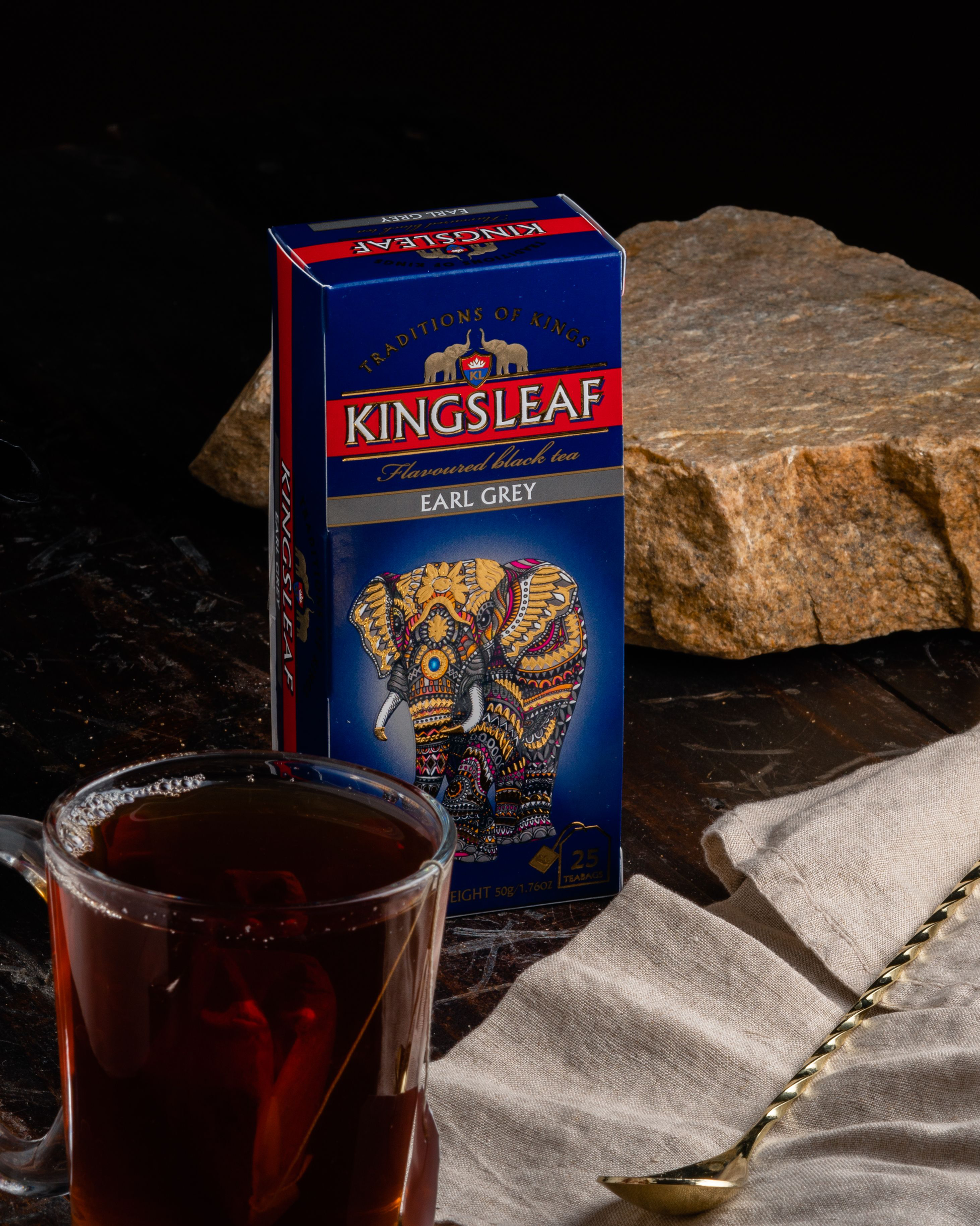 Pudełko herbaty Kingsleaf Earl Grey obok filiżanki z ciemnym naparem i łyżeczką.