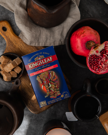 Pudełko herbaty Kingsleaf English Breakfast w otoczeniu granatów, cukru trzcinowego i ceramiki.