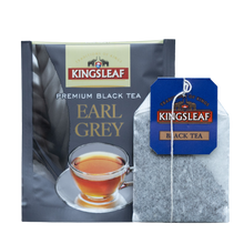 Herbata Kingsleaf Earl Grey w pojedynczej kopercie, obok torebka herbaty ze sznurkiem i niebieską zawieszką z logo Kingsleaf.