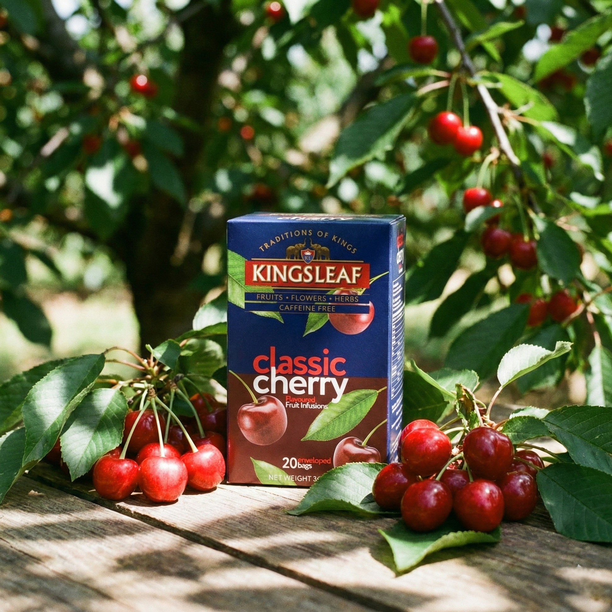 Pudełko herbaty Kingsleaf Classic Cherry wśród świeżych wiśni na drewnianym stole w sadzie.