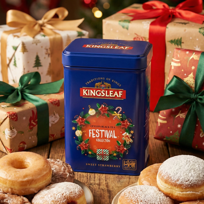 Puszka herbaty Kingsleaf Festival Sweet Strawberry w świątecznej aranżacji z prezentami i pączkami na drewnianym stole.