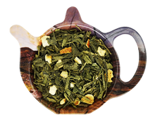 Zielona herbata Sencha Grapefruit z kawałkami grapefruita w naczyniu w kształcie czajniczka, aromatyczna mieszanka cytrusowa.