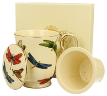 Komplet: kubek porcelanowy Ecru Ważka 450 ml, przykrywka i zaparzacz, zaprezentowane na tle pudełka prezentowego.