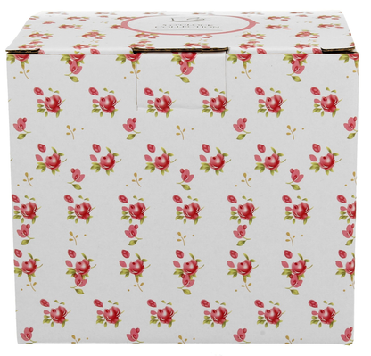 Białe pudełko ozdobione drobnym, różowym wzorem kwiatów, w którym zapakowany jest porcelanowy kubek z zaparzaczem Eleni.