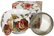 Zestaw: kubek porcelanowy Kasandra 530 ml, zaparzacz i pokrywka na tle ozdobnego pudełka prezentowego.