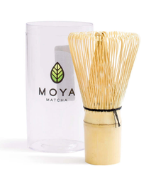 Bambusowy pędzelek do matchy chasen obok przezroczystego opakowania z logo Moya Matcha.