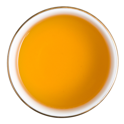 Złocisty napar herbaty ziołowej Basilur Immunity z hibiskusem, kurkumą, mango i ananasem w filiżance.
