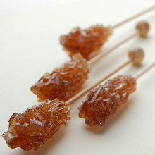 Zbliżenie na kryształki brązowego cukru na patyczkach 17 cm.