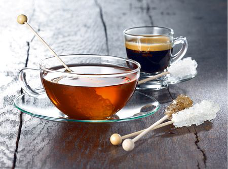 Filiżanka herbaty i espresso z pałeczkami cukrowymi białymi i brązowymi.