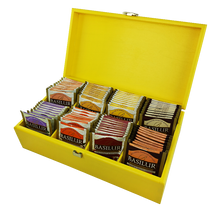 Otwarty ekspozytor z żółtego drewna z różnorodnymi smakami herbat Basilur w kopertach.