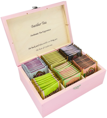 Drewniane pudełko Basilur w różowym kolorze z zestawem herbat w saszetkach.