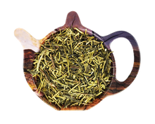 Suszona herbata China Kukicha Organic w formie łodyżek i listków, ułożona w drewnianym czajniczku.